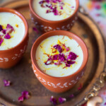 Thandai served in 3 cups, garnished with saffron and rose petals