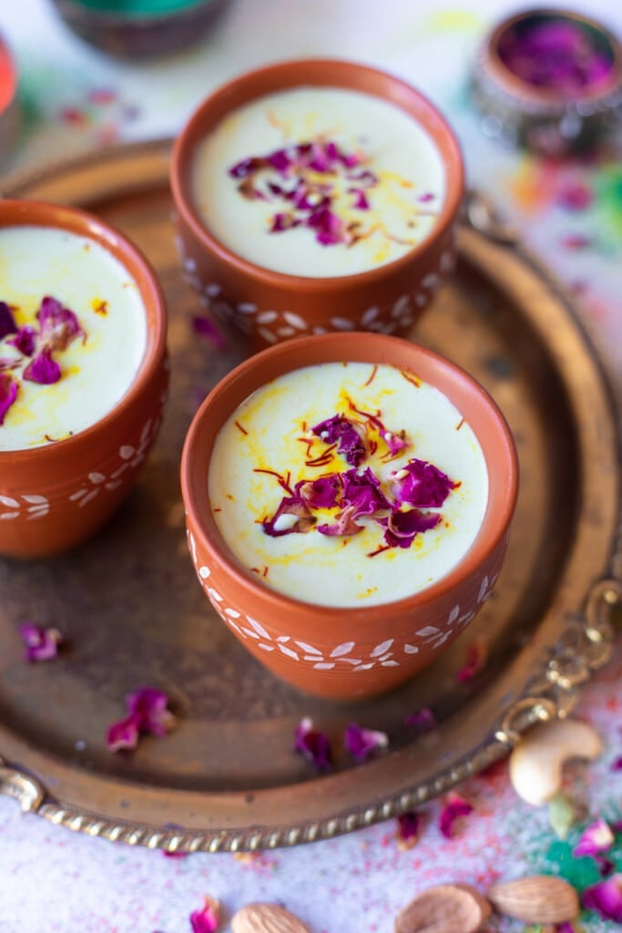 Thandai served in 3 cups, garnished with saffron and rose petals