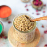 Thandai Powder in a pretty jar with rose petals and holi colors on the side