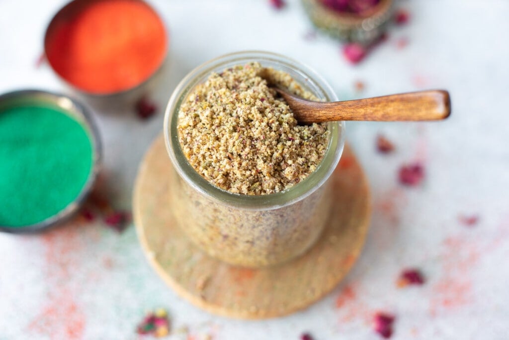 Thandai Masala in a jar with holi colors spread around