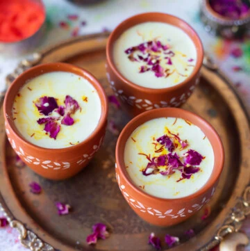 Thandai served in 3 glasses for Holi garnished with rose petals and saffron strands