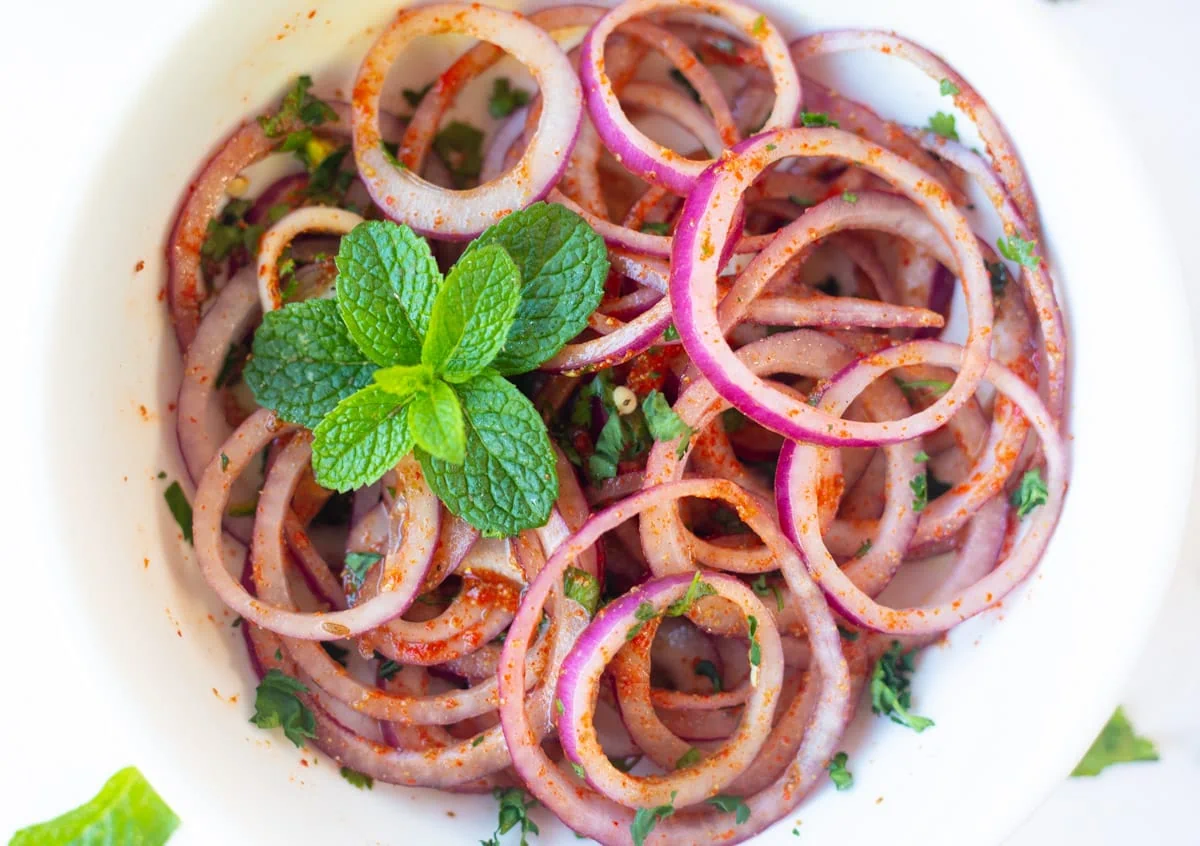 masala onion salad garnished with mint leaves