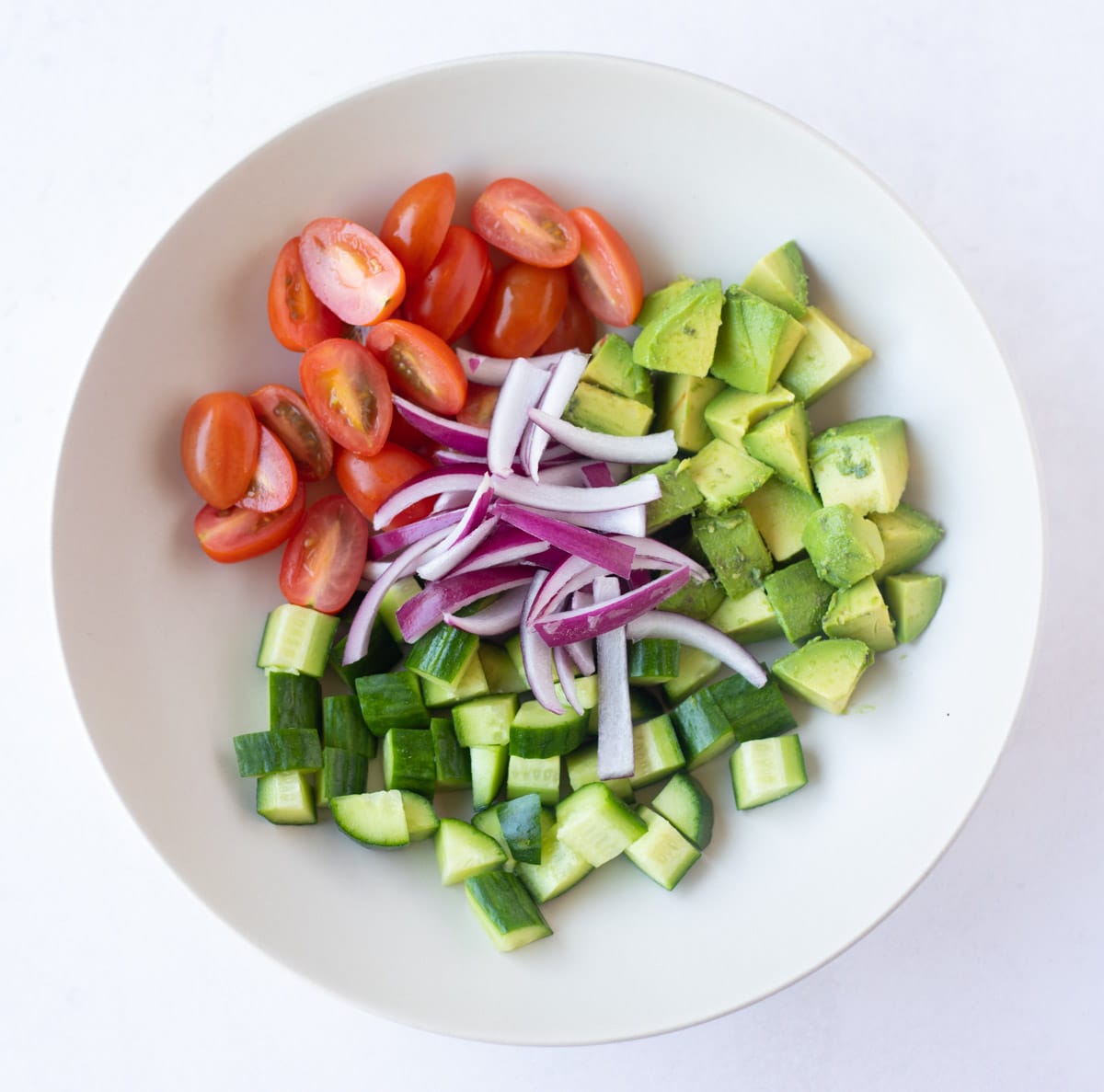 Avocado, cucumber, tomato, red onions in a bowl to make salad 