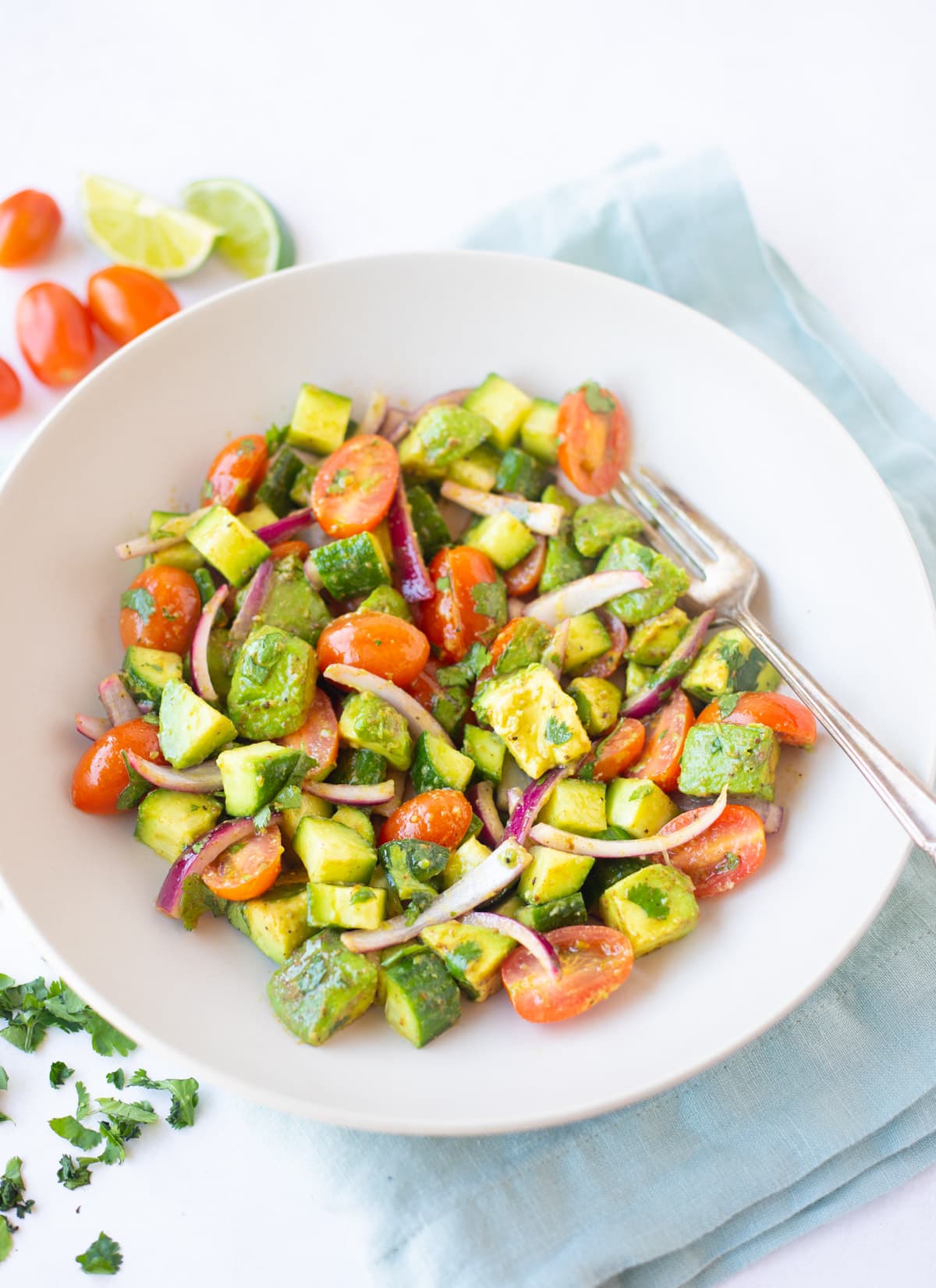avocado cucumber tomato salad with lime dressing and chaat masala in a bowl 