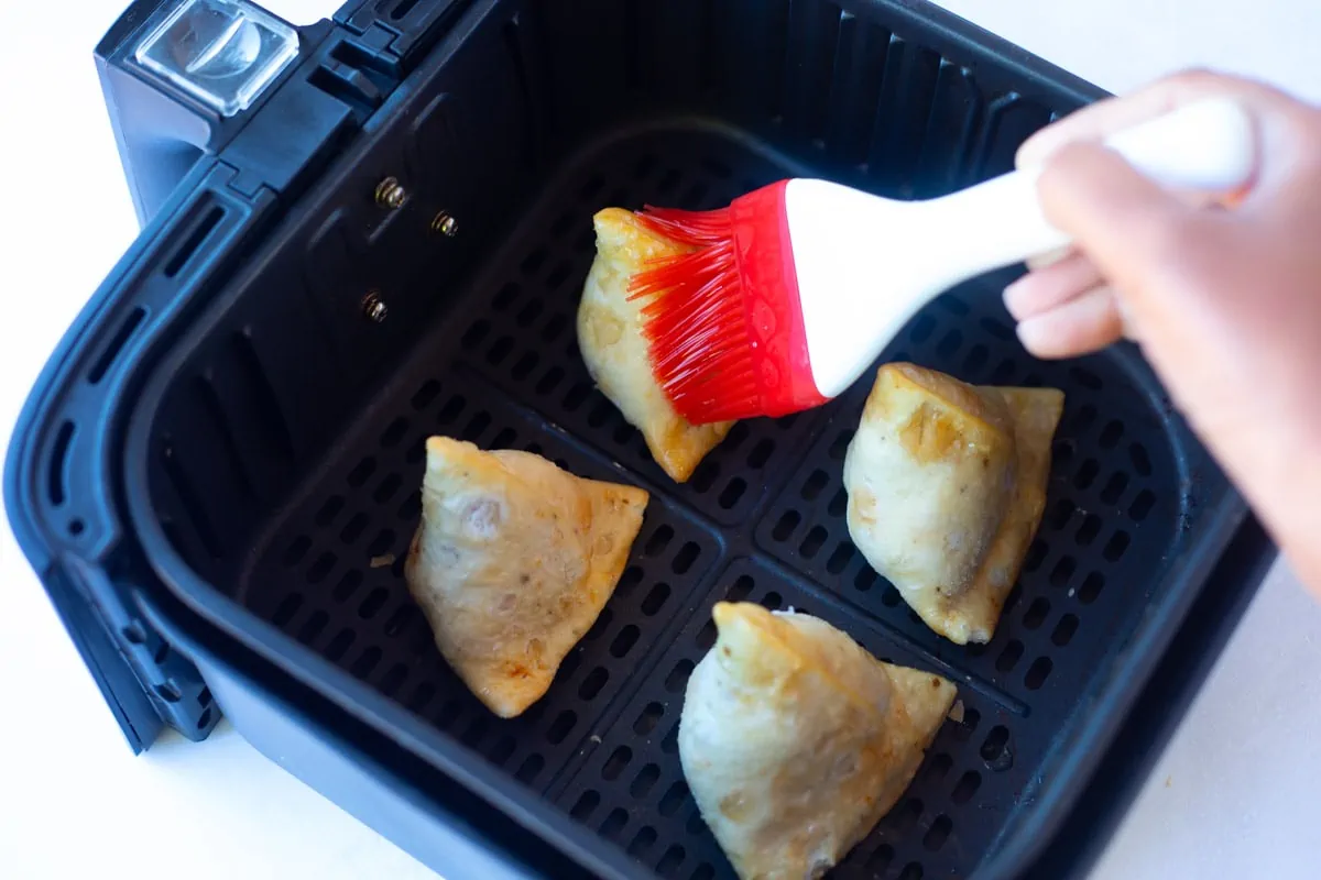 Brushing oil on frozen samosa to be cooked in the air fryer