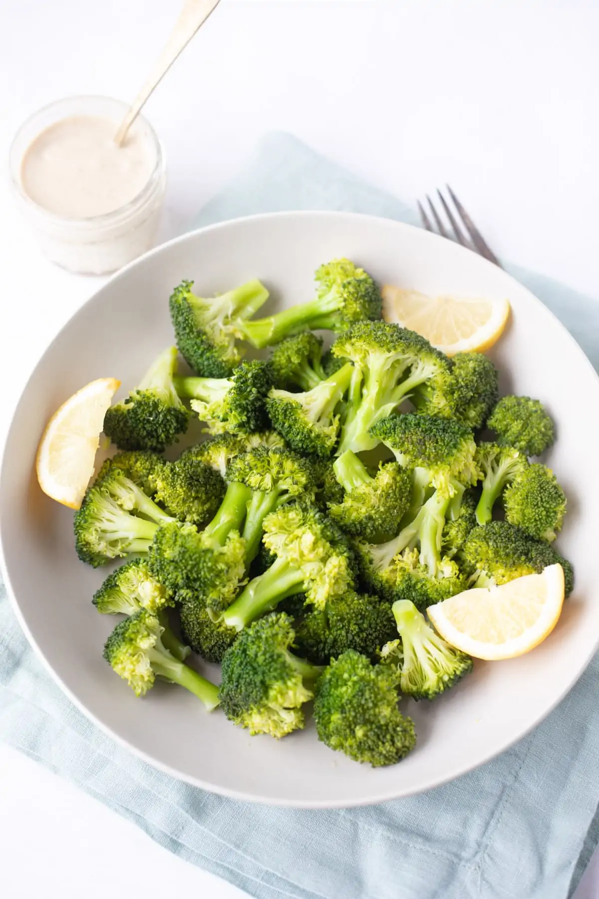 perfectly steamed broccoli made in the instant pot served in a bowl with lemon wedges