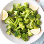 Steamed instant pot broccoli in a bowl with lemon wedges