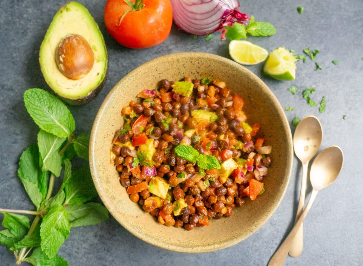 Kala Chana Chaat in a bowl with tomato, onions and lime on the side