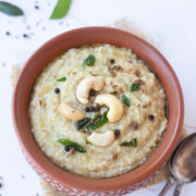 Millet Pongal topped with tempering of cashews and curry leaves in a bowl