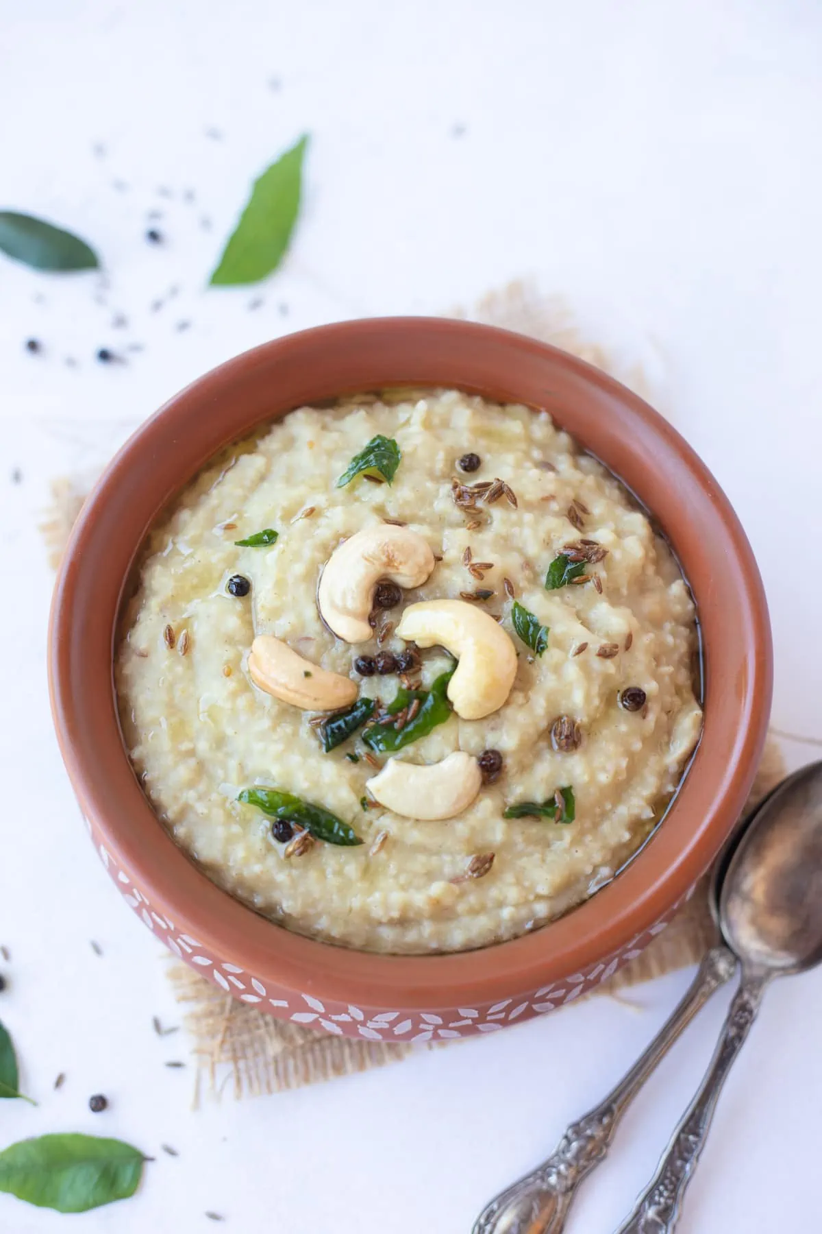 Millet Pongal topped with tempering of cashews and curry leaves in a bowl 