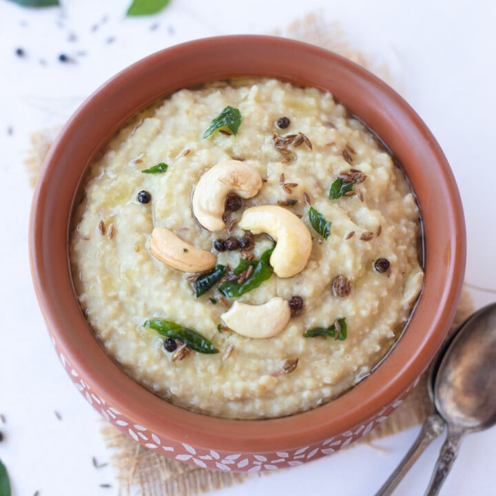 Millet pongal garnished with a tempering of cashews and curry leaves