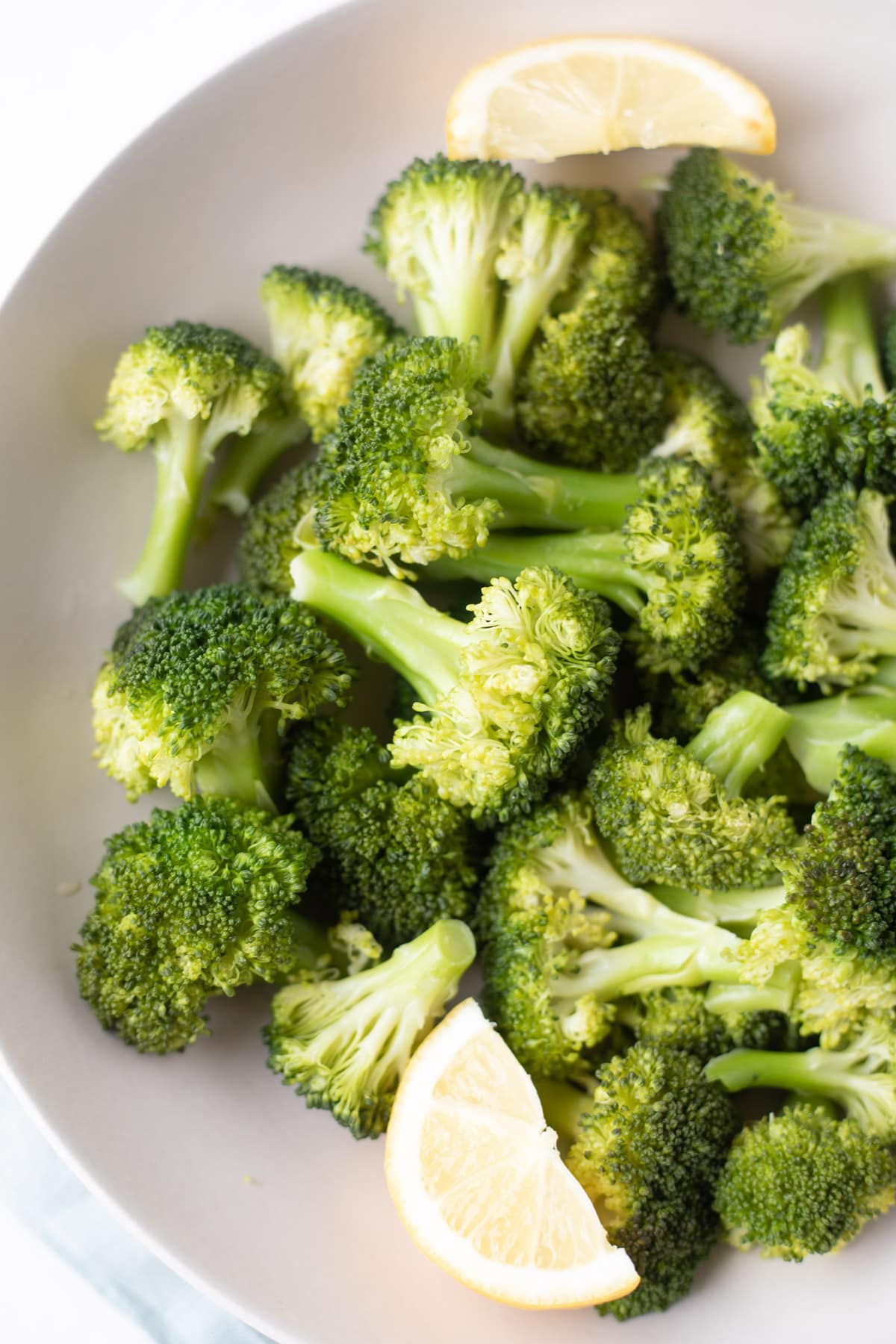 Steamed instant pot broccoli in a bowl with lemon wedges 