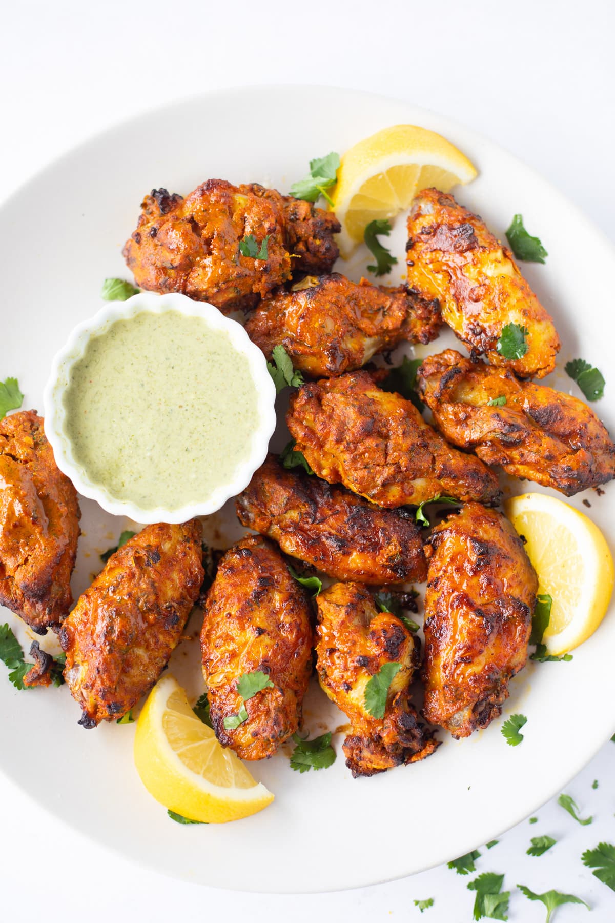 Tandoori chicken wings served in a plate with green chutney 