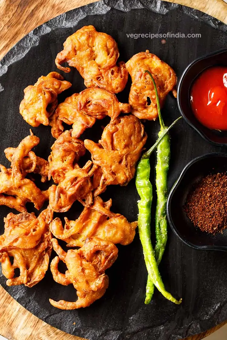 Onion pakora on a platter with green chili and a dip 