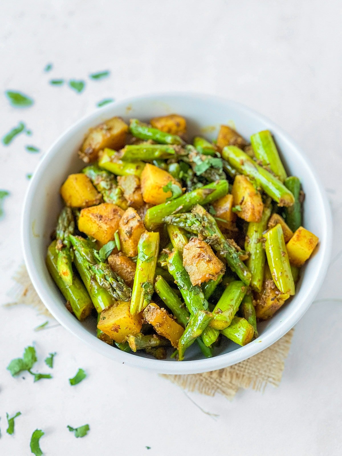 Indian asparagus and potato stir fry in a white bowl 