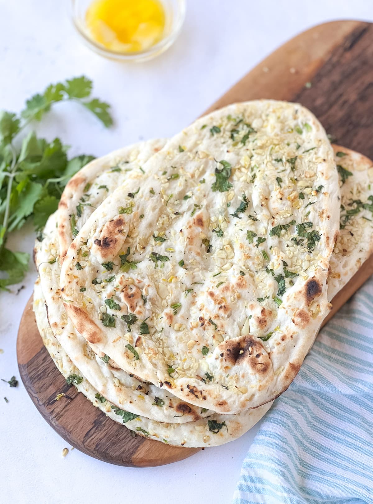 Reheated naan on a platter with cilantro and butter on the side