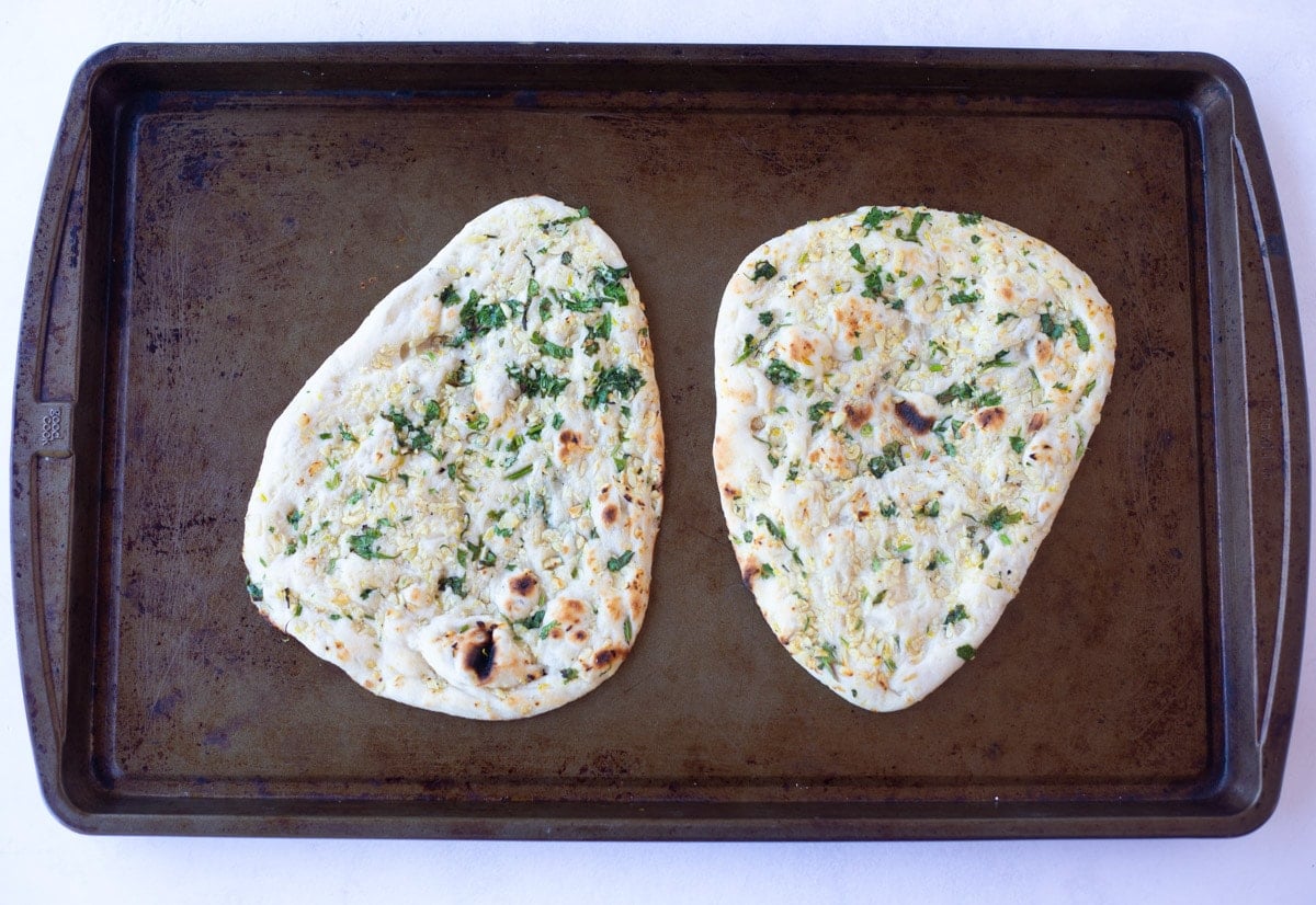two naan on a baking sheet to be reheated in the oven
