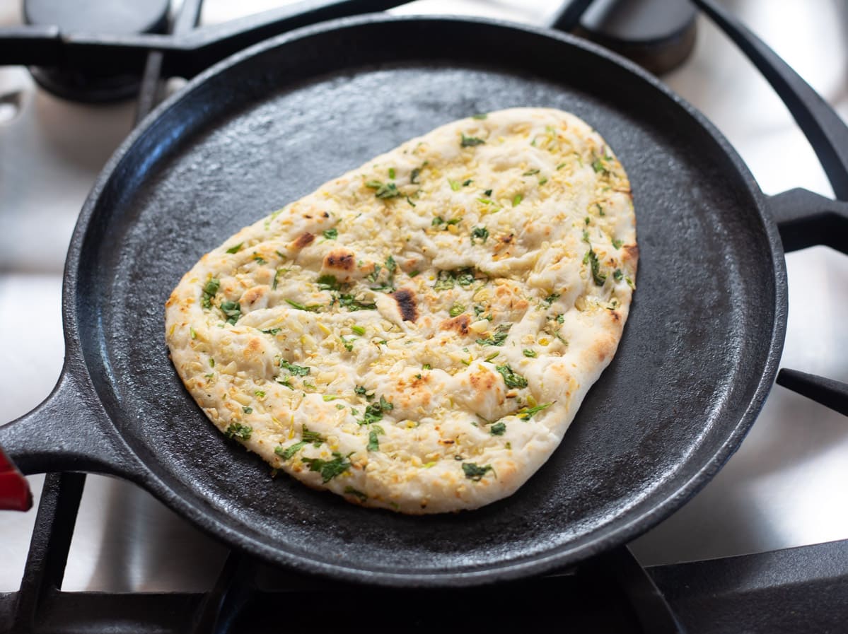 Naan being reheated in a pan on stovetop 