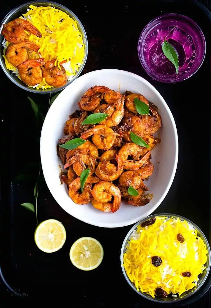 Kerala Prawn Roast in a serving plate side with rice, lime and juice