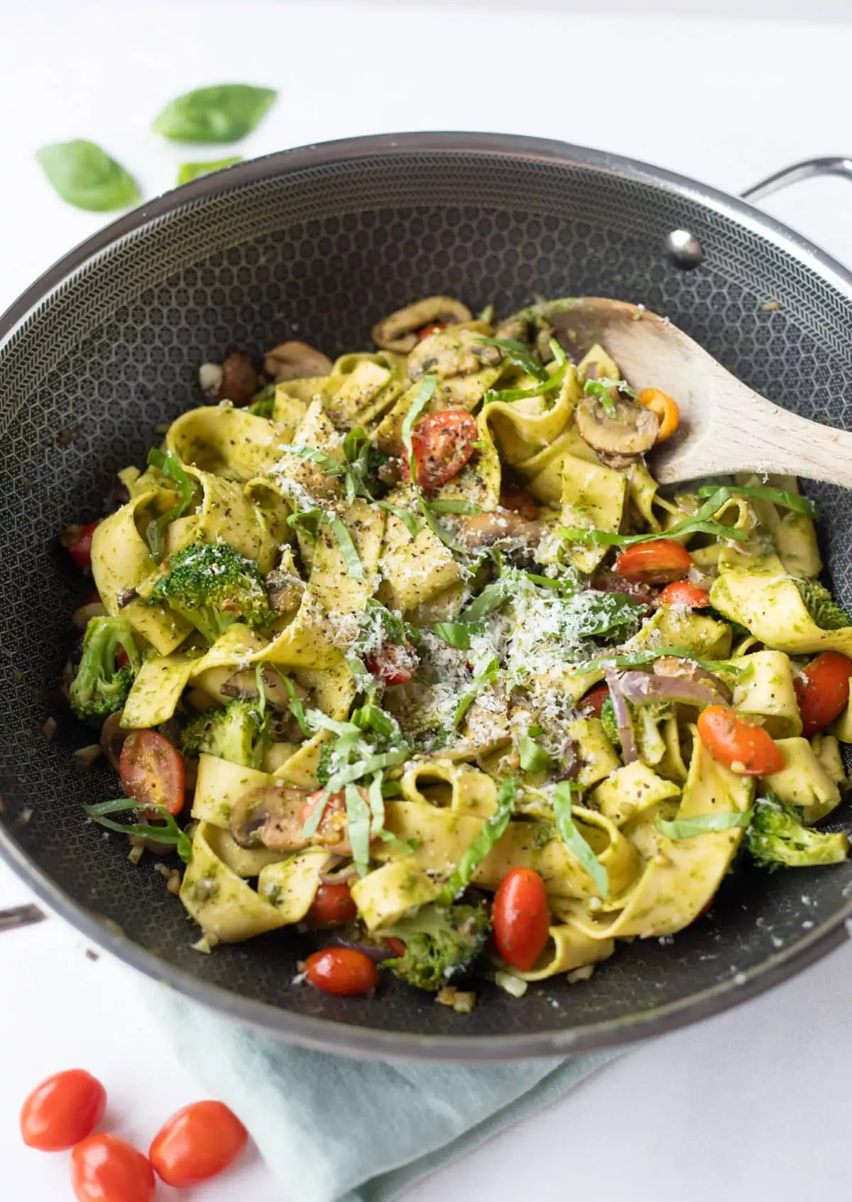 Pappardelle pasta with vegetables topped with basil and parmesan in a large pan 