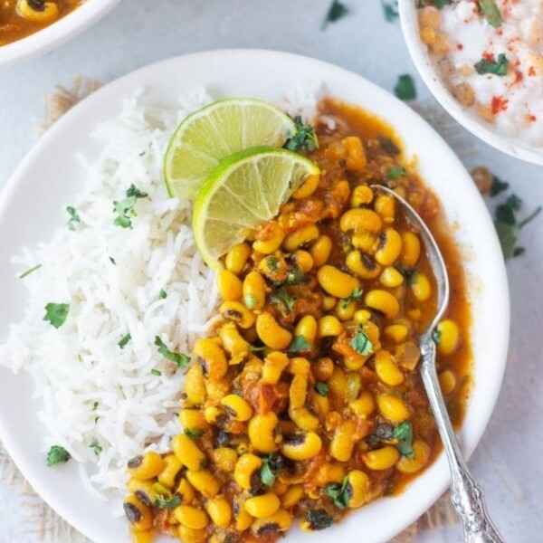 Black eyed peas curry in a bowl garnished with cilantro and rice and yogurt on the side