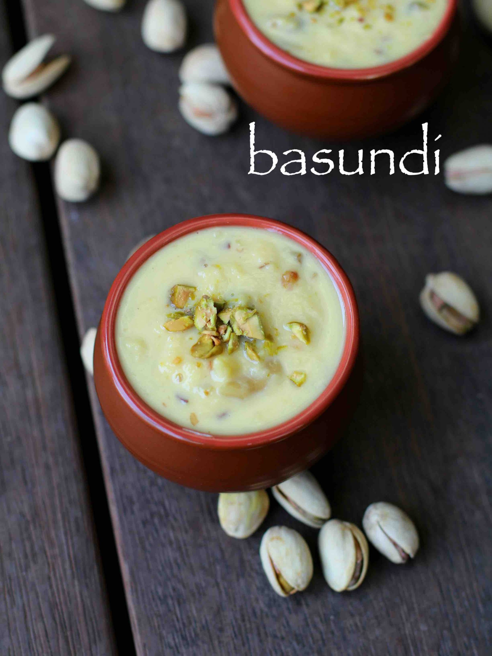 Basundi in a small brown pot with nuts on side