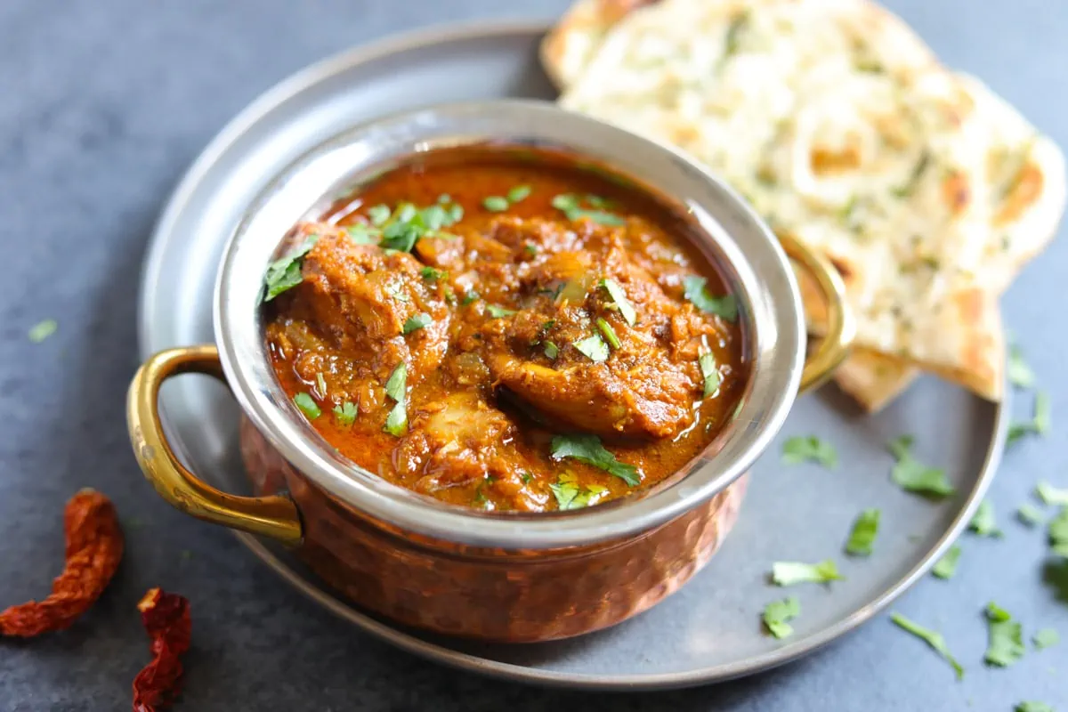 Instant pot chicken vindaloo in a bowl with naan on the side 