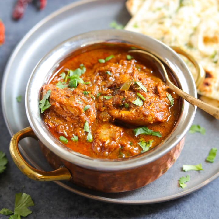 chicken vindaloo curry in a bowl with naan on the side