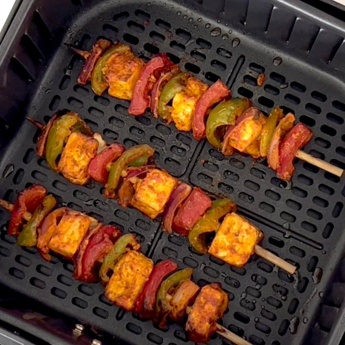 Slightly cooked paneer tikka in air fryer basket