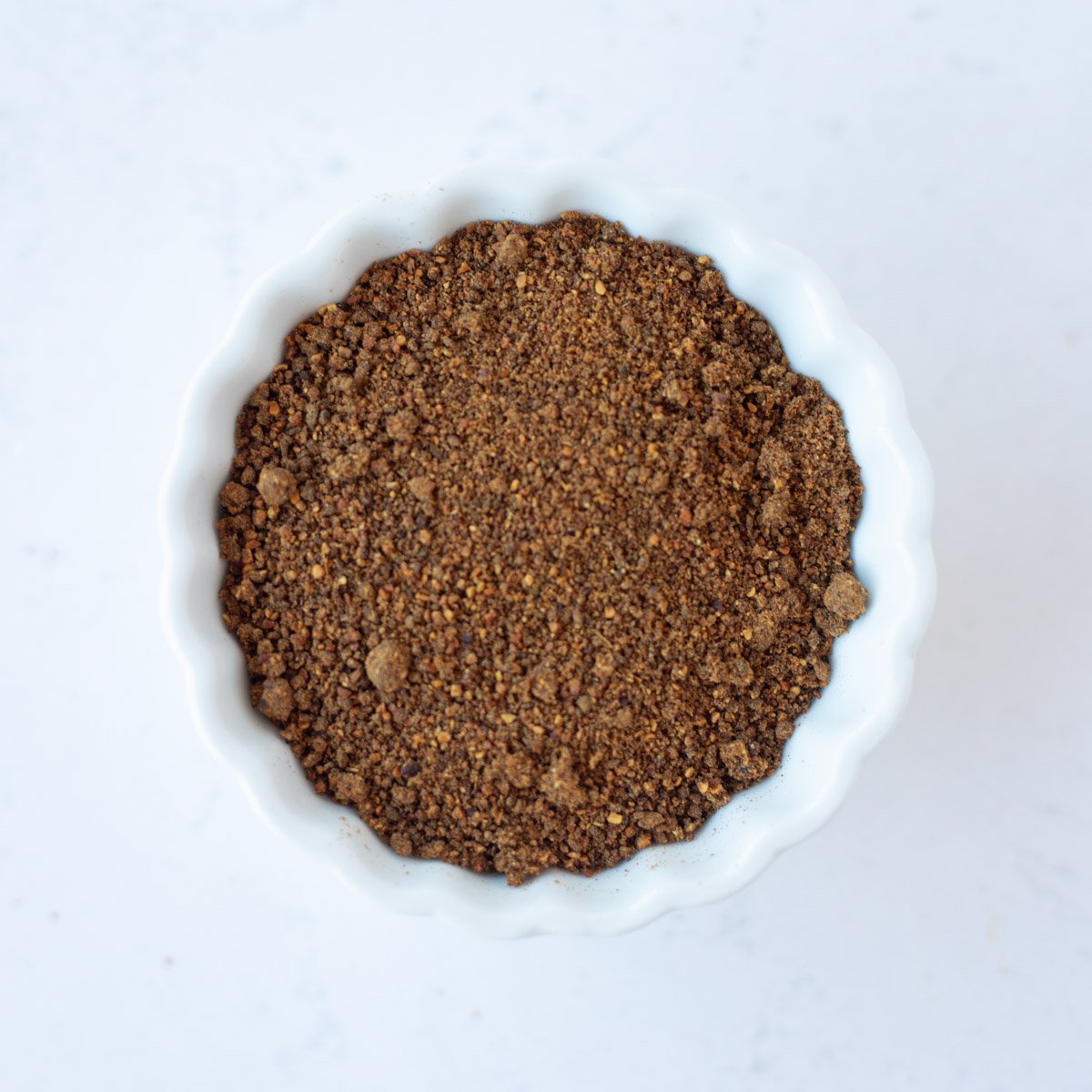 Pomegranate seeds powder in a small white bowl.