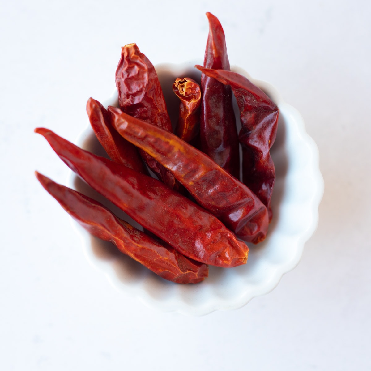 Dried red chili peppers in a small white bowl.