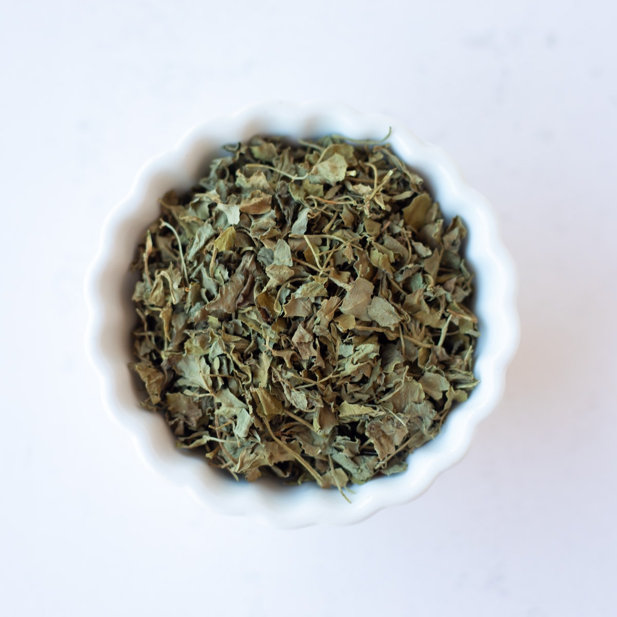 Dried fenugreek leaves in a small white bowl.