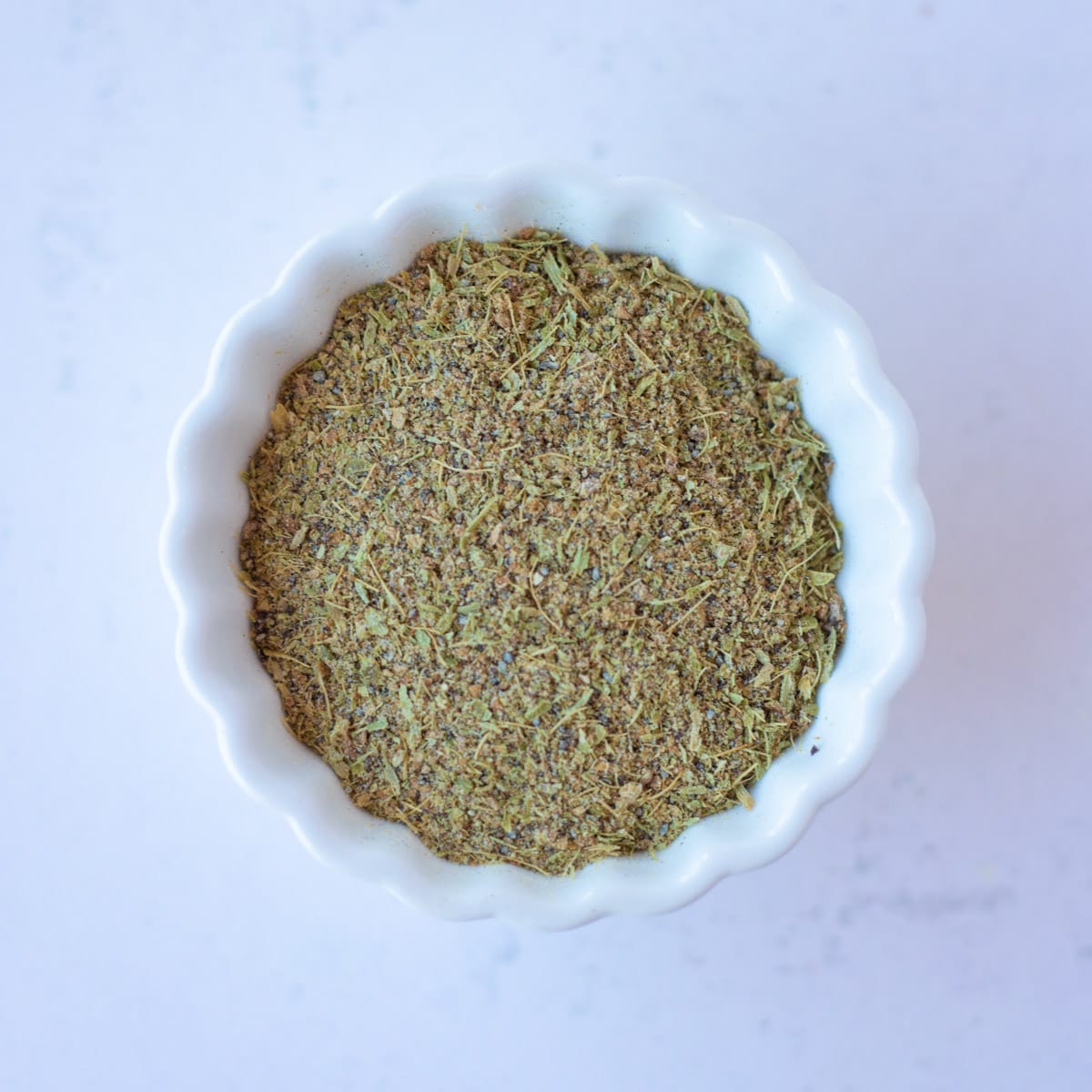 Ground Cardamom powder in a small white bowl.