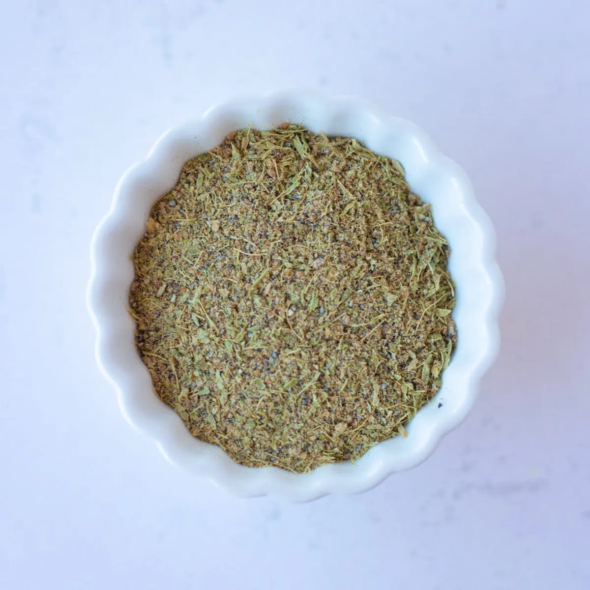 Ground Cardamom powder in a small white bowl.