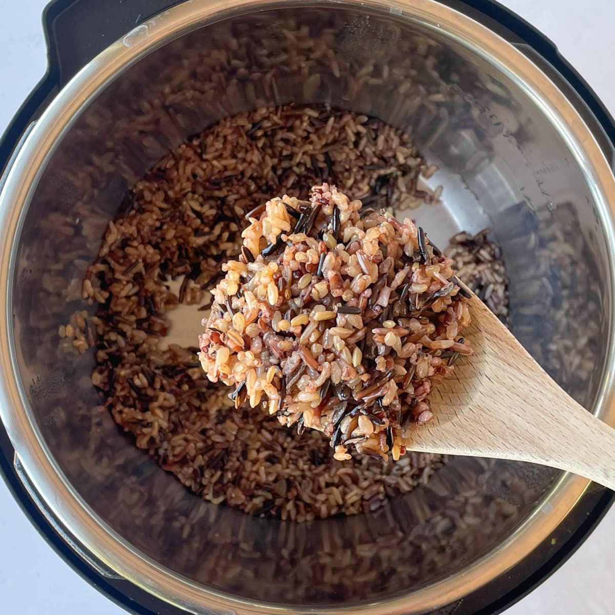 Cooked wild rice blend in a ladle on top of the instant pot