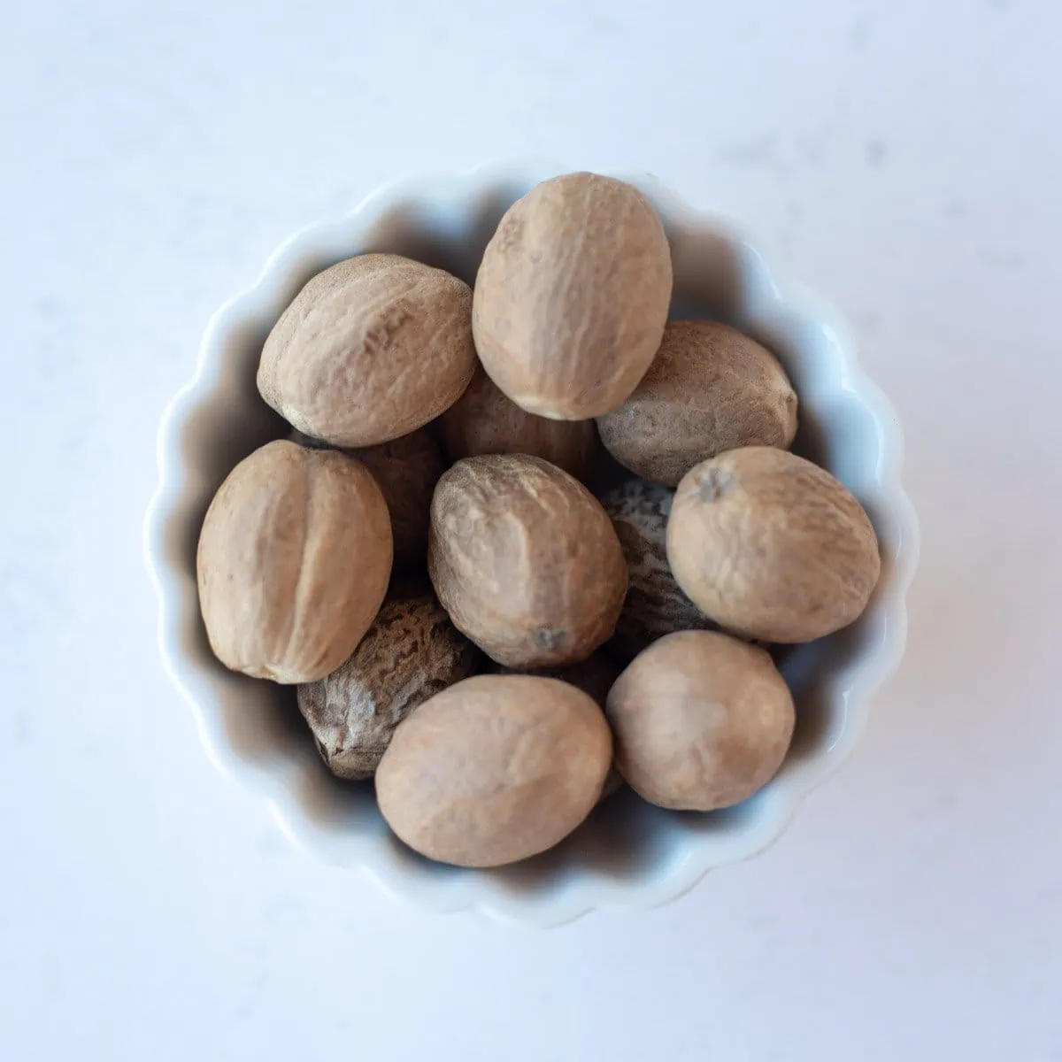 Nutmeg seeds in a small white bowl