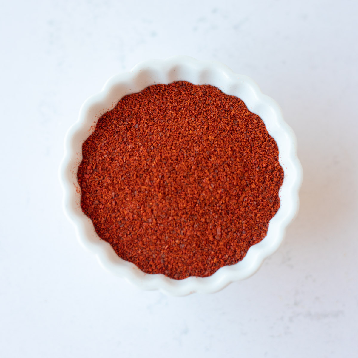 Red chili powder in a small white bowl.