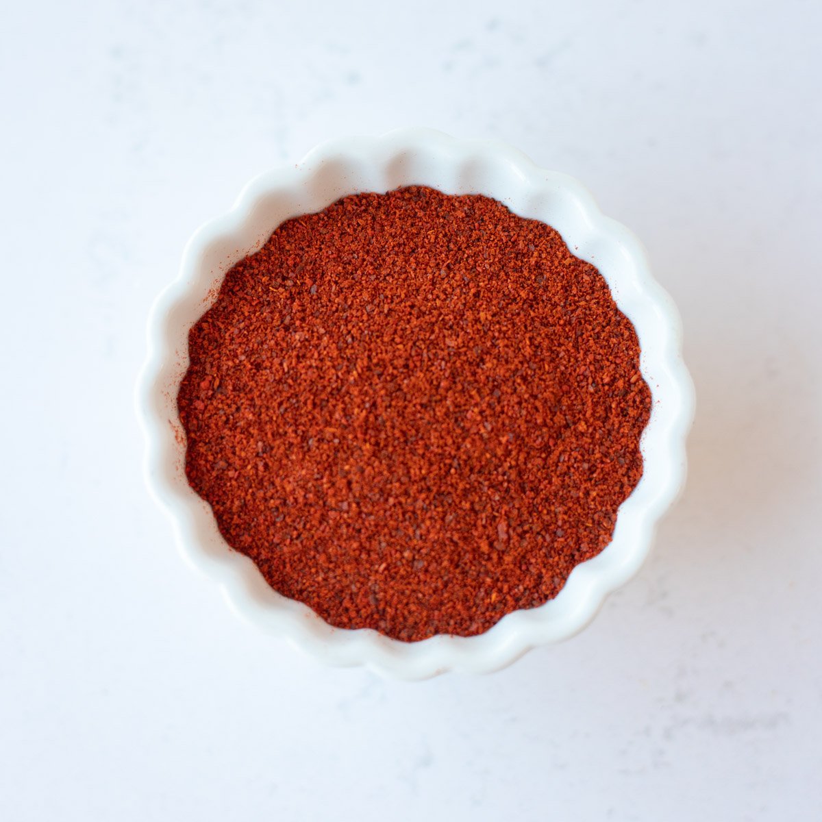 Red chili powder in a small white bowl.