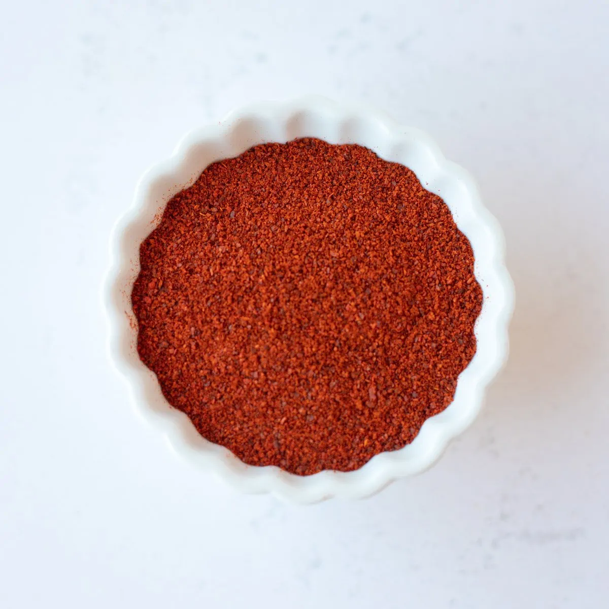 Red chili powder in a small white bowl.