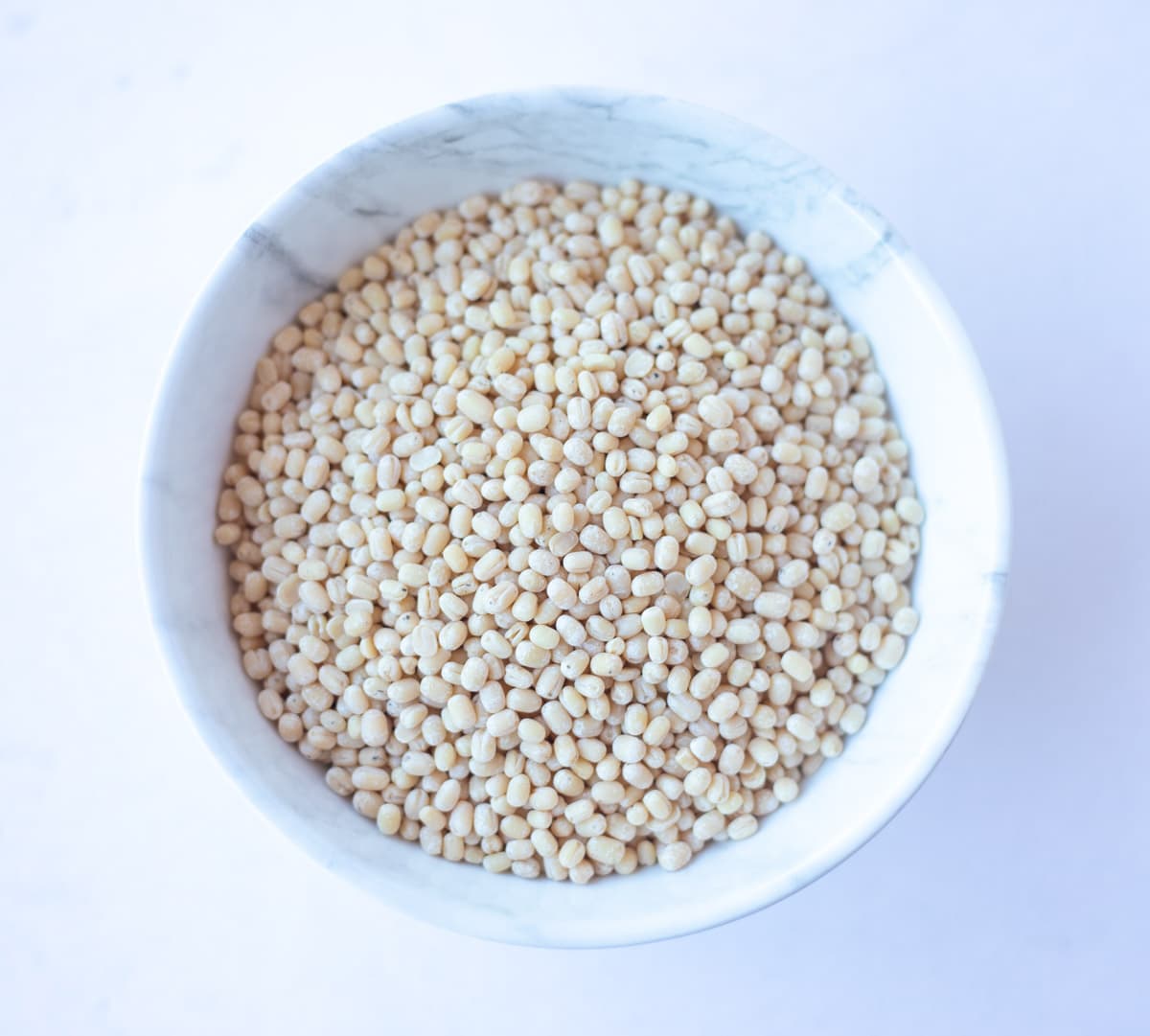 Skinned black gram (urad gota) in a white bowl 