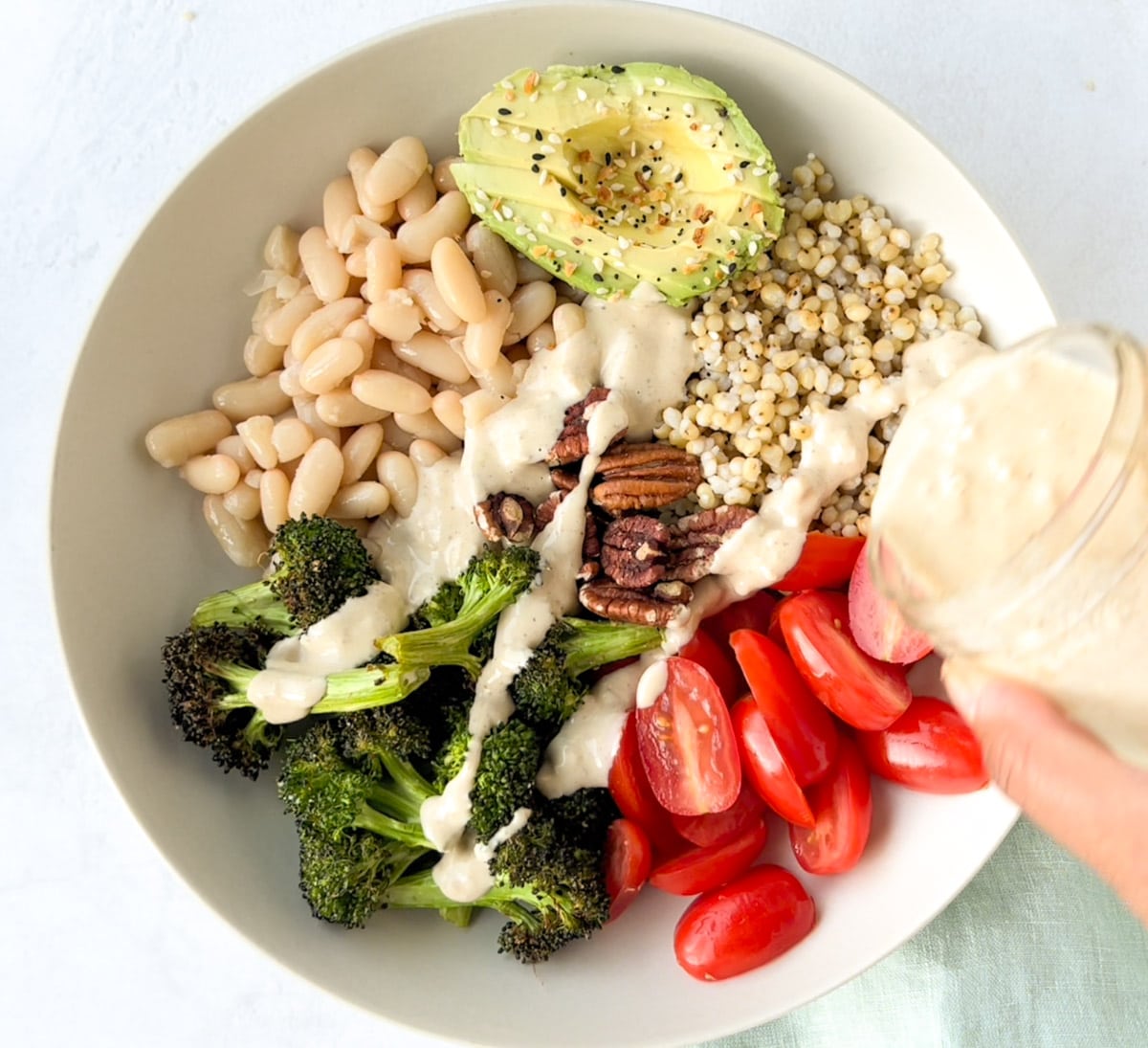 A vegan sorghum buddha bowl with with Beans, veggies, topped with dressing 