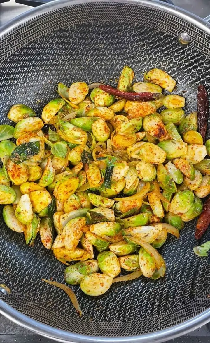 Spiced curried brussels sprouts being cooked in a pan