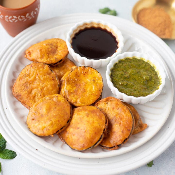 deep fried baingan pakora in white plate with dips