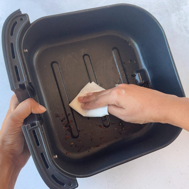 Clean crumbs in air fryer basket with a paper towel