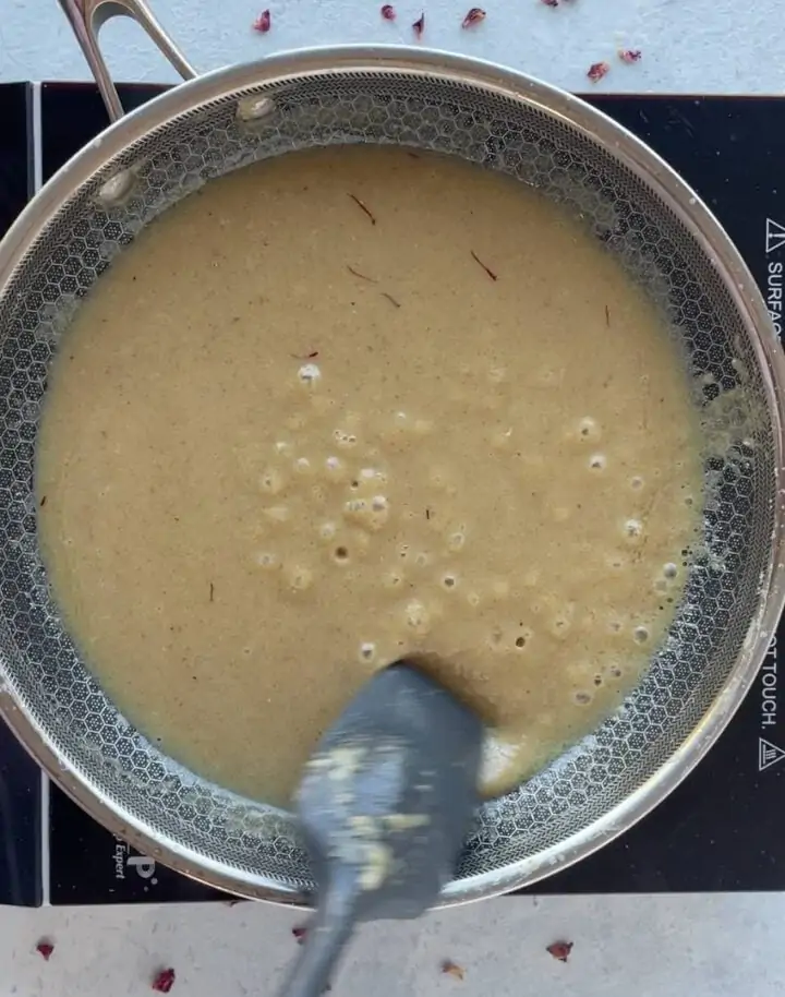 mixing ingredients for badam halwa until it thickens