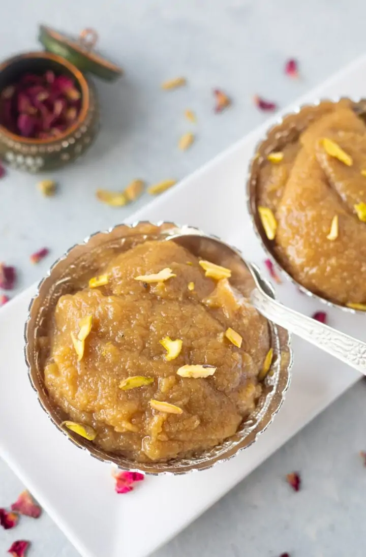 Badam ka halwa topped with pistachios in a silver bowl