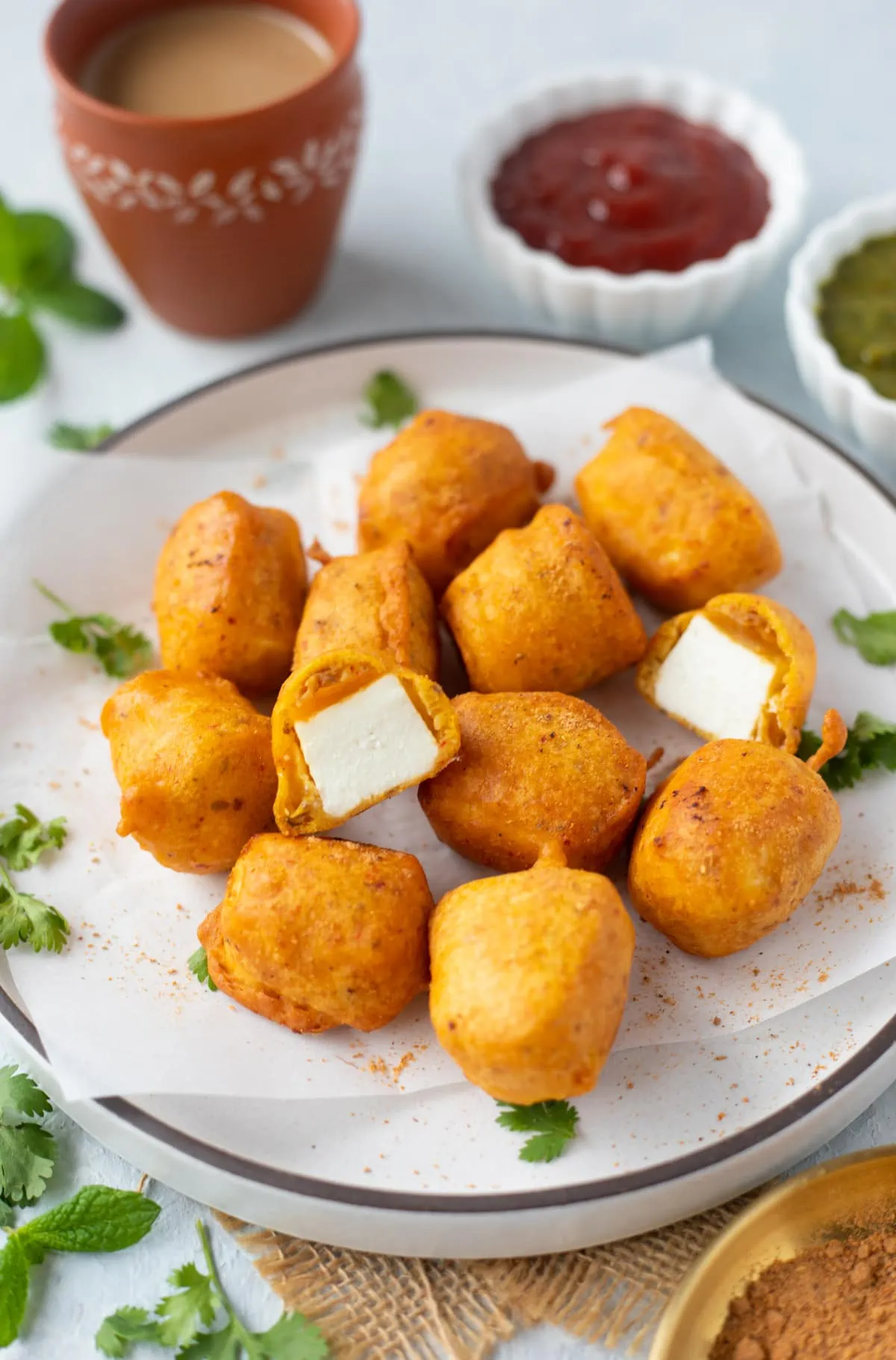 Crispy Paneer Pakora in a white plate and parchment paper
