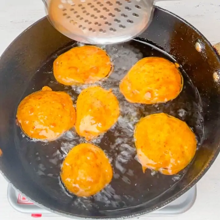 eggplant pakoda getting fried in a black kadai