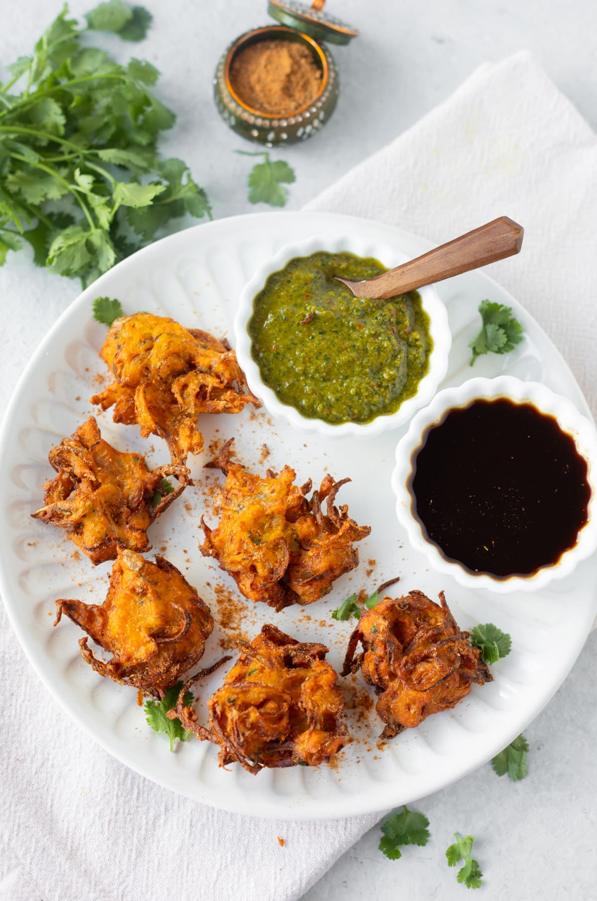 Onion Pakora in a white plate with chutneys