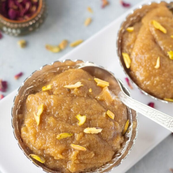 Badam ka halwa topped with pistachios in a silver bowl
